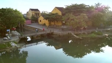 Antik Hoian historial bölgesinde küçük yaya köprüsü ile sahildeki eski sarı iki katlı evler 