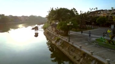 kadının eski Hoian fitness sabah yapması için palmiye ağaçları ile güzel modern riverfront boyunca hareket