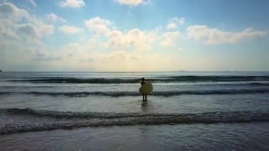 Sörf yapmak için turkuaz okyanusa dron görünümü kadın siluet mayo gider