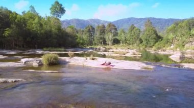 üst görünüm uzak kadın şekilde yoga poz taş ve ön plan üzerinde dönen nehir suyu