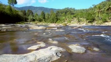 Panorama uzak kadın yoga egzersiz rapids ve avuç içi akış karşı kayaya oturan gerçekleştirir