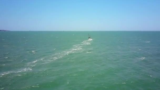 空中パノラマ孤独なウインドサーファー図は無限の青い空の下の地平線に巨大な永遠の海に帆します — ストック動画