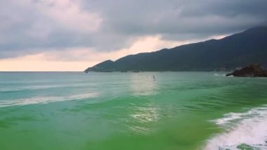 dalgalar için yalnız ince kız şafakta gökyüzü bulutlu karanlık tepelik sahilinde masmavi okyanusta yelken paddleboard üzerinde haddeleme gelen şaşırtıcı uçuş