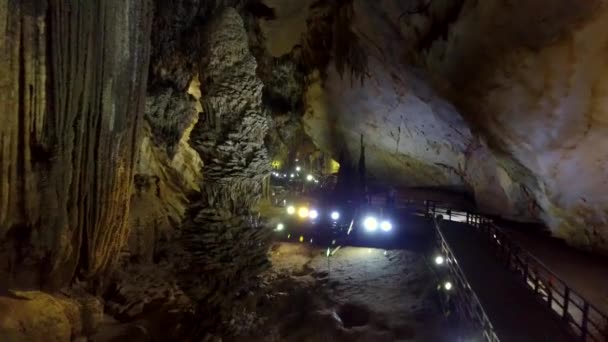 通过桥过去奇异的石笋柱到洞穴中央大厅点亮的墙壁 让五颜六色的灯光惊人的接近运动 — 图库视频影像