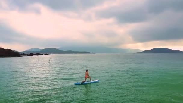 Girl drifts on paddleboard in pose Crescent Lunge Twist on Knee — Stock Video