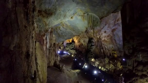 前景に鍾乳石や石筍の構造と巨大な列とプロジェクターに照らされて神秘的な地質カルスト洞窟 — ストック動画