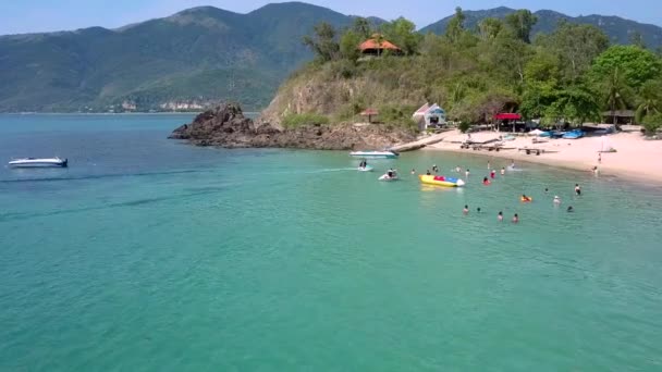 水泳の人々 とボート緑の丘に対してエキゾチックな砂浜と紺碧の海の端に素晴らしいビュー モーション — ストック動画