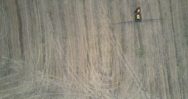 空中垂直视图拖拉机尾随喷雾器为肥料驱动在褐色收获的领域做踪影 — 图库视频影像