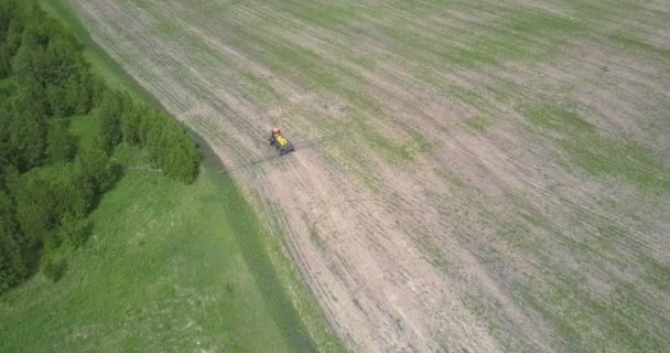 图片鸟瞰拖拉机移动棕色条纹最近收获的领域之间的绿色树林 — 图库视频影像
