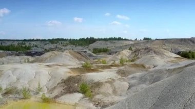 terk edilmiş kil ocağı sarı su birikintisi ve mavi gökyüzü altında nadir bitkiler ile garip üst panorama sınırsız alan