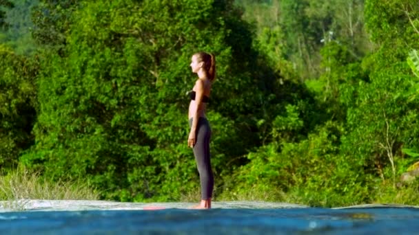 Blond flicka böjer kroppen i yogaställning på löpande ström bank — Stockvideo