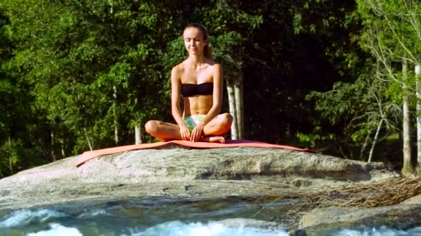 Joven mujer relaja en posición medio loto por río espumoso — Vídeo de stock