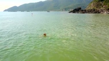 kız yeşil tepeler karşı sakin okyanusta yüzüyor