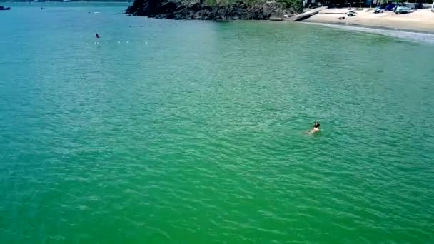 Vrouw zwemt in azuurblauwe Oceaan naar groene strand — Stockvideo