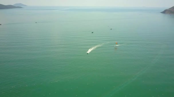 Barco a motor con rastro espumoso tira del paracaídas en el océano — Vídeo de stock