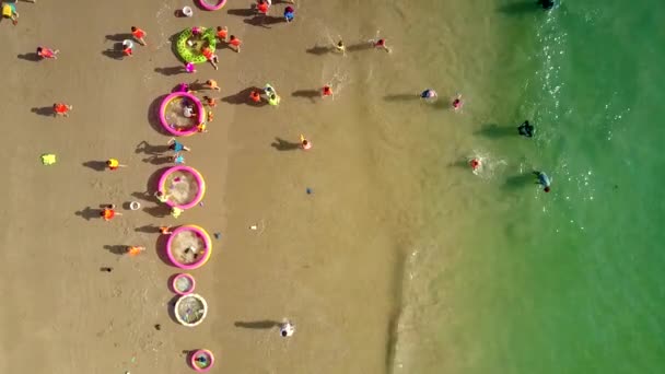 Niños corren por la playa oceánica entre piscinas neumáticas — Vídeos de Stock