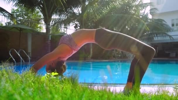 Sportliches Mädchen hält an sonnigem Tag Bogen nach oben am Pool — Stockvideo