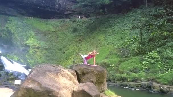 Kız yoga poz yüksek kayanın üzerinde yeşil yamaç tarafından tutar — Stok video