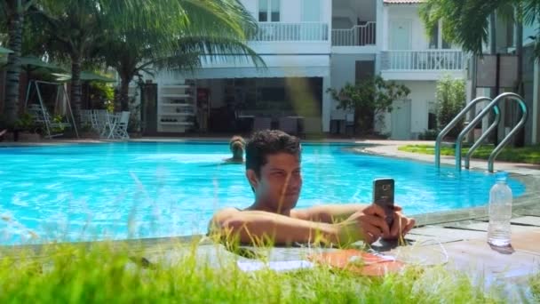 Κυρία κολυμπά σε πισίνα άντρας στέκεται στο νερό στο φράγμα — Αρχείο Βίντεο