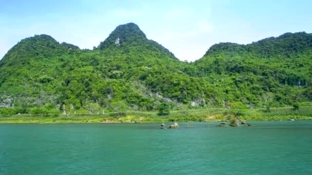 Gerak melewati perbukitan hutan di tepi sungai di bawah langit biru — Stok Video