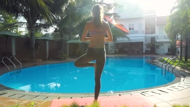 Zadní pohled dívka stojí v jóga představuje bazénu ráno — Stock video
