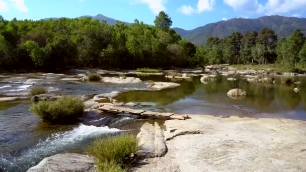 Rapides fluviaux coulent sous le pont sur les pierres contre les collines verdoyantes — Video