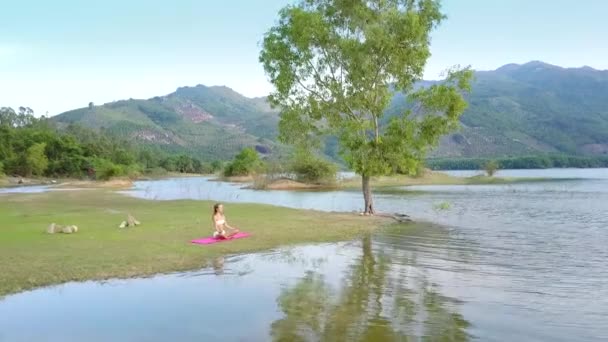 Wind schudt boomtakken weerspiegeld op het water door meisje — Stockvideo