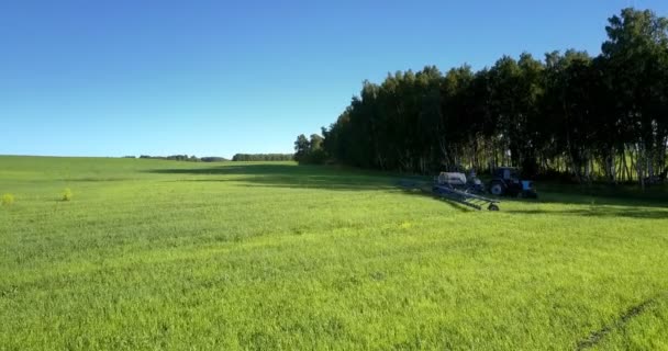 Getrokken spuitmachine draait rechts in bomen schaduw op groene veld — Stockvideo