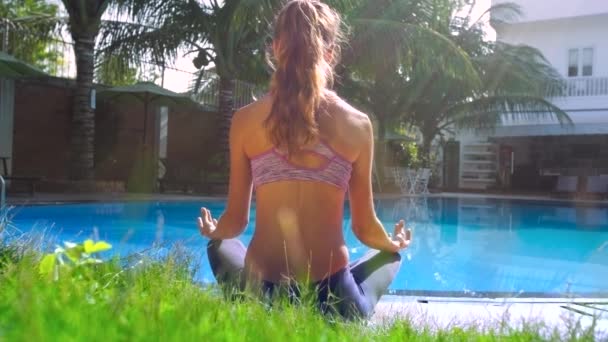 Señora relaja sentado en yoga pose por piscina vista trasera — Vídeo de stock