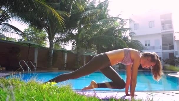 Senhora faz Legged Downward-Facing Dog ioga posições por piscina — Vídeo de Stock