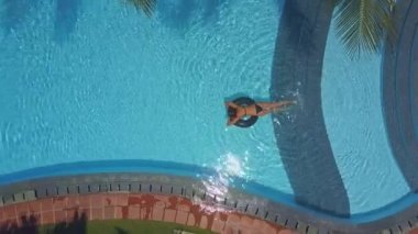 Lifebuoy kavurucu güneş ışınları altında mavi havuzu üzerinde panoramik kadın siyah mayo yelken