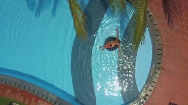 Meisje in bikini ligt op rug op ring in blauwe zwembad — Stockvideo