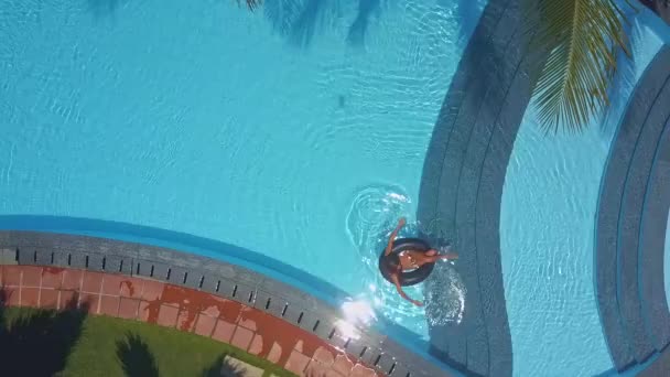 Girl sits in ring and paddles across pool — Stock Video