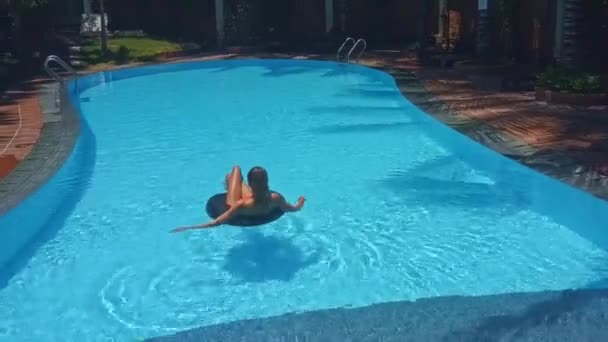 Achterkant meisje ligt op opblaasbare ring in zwembad — Stockvideo