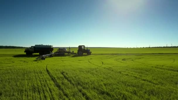 Traktor fyller kemikalier från cistern på väg bland gröna fält — Stockvideo