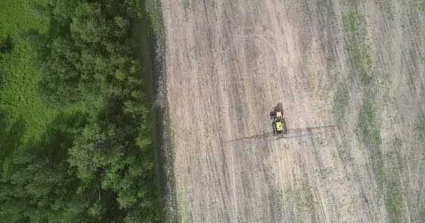 Unidades de trator de visão aérea no campo colhido ao longo da floresta — Vídeo de Stock