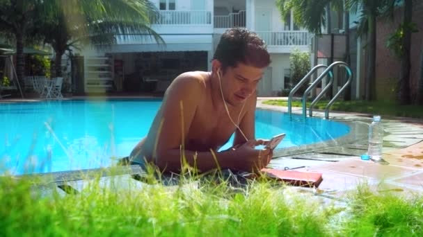 Cara surfa internet através de smartphone por barreira piscina — Vídeo de Stock