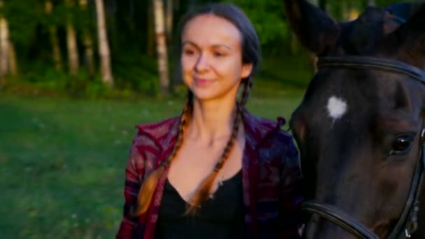 Closeup mooi meisje leidt paard onder hoofdstel in de buurt van bos — Stockvideo