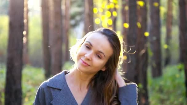 Nice blond girl touches long hair lit by back sunset rays — Stock Video