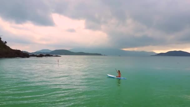 Frau paddelt an Bord im Ozean gegen Inseln — Stockvideo