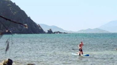 okyanus plaj paddleboard üzerinde çömelme adam yaklaşıyor