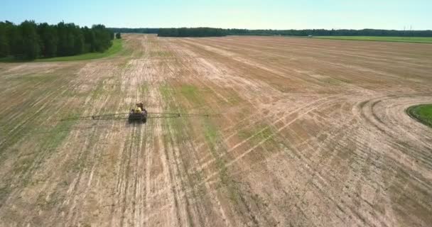 Fertilizer spreader with long bars drives along harvested field — Stock Video
