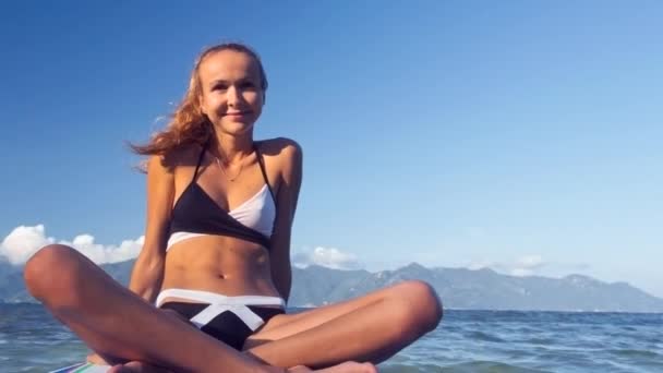 Blond langharige meisje zeilen aan boord van de peddel aan Oceaan — Stockvideo