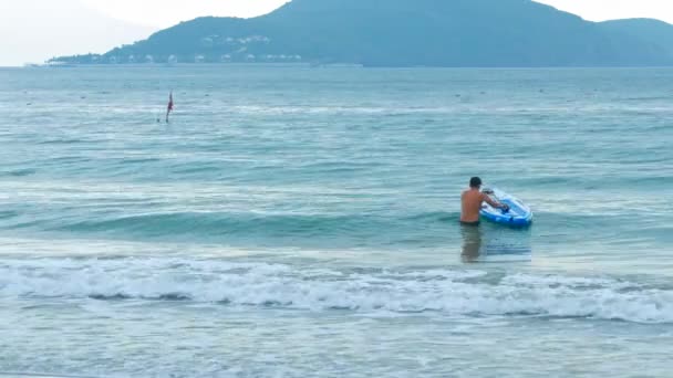 Chlap jde v oceánu dostane na prkno proti beach — Stock video