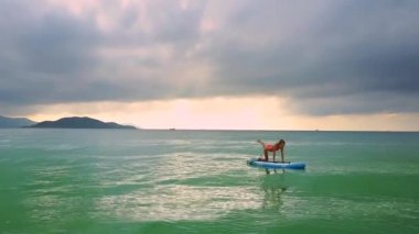 görünümü Kapat kız yoga poz paddleboard bulutlar altında üzerinde