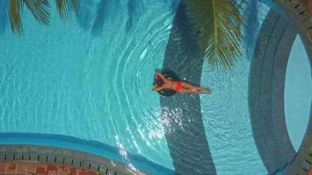 Kobieta w bikini sunbathes na pierścieniu w hotelowym basenie — Wideo stockowe
