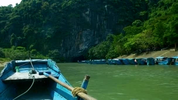 Barco flota más allá de los barcos turísticos azules amarrados a la orilla — Vídeos de Stock