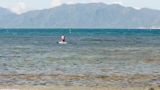 Чоловік стоїть на колінах ряди весло в океані — стокове відео
