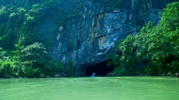 Camera follows boat moving to grotto under rock by river — Stock Video