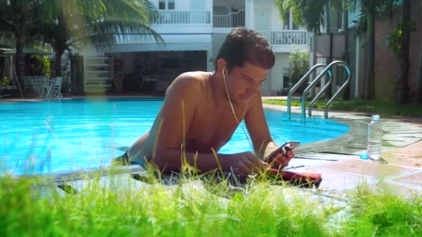Jovem coloca de lado telefone olha através de diário de papel por piscina — Vídeo de Stock